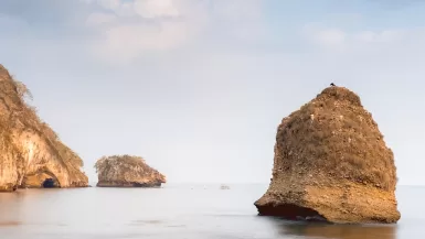 a rocky beach with two large rocks sticking out of the water in Mismaloya