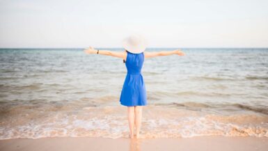 15 Fun Activities for the Best Beach Vacation 7 a woman in a blue dress standing on a beach Beach Vacation