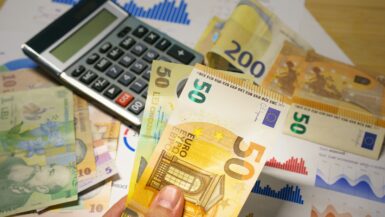 A person holding a bunch of money next to a calculator Smart Spending