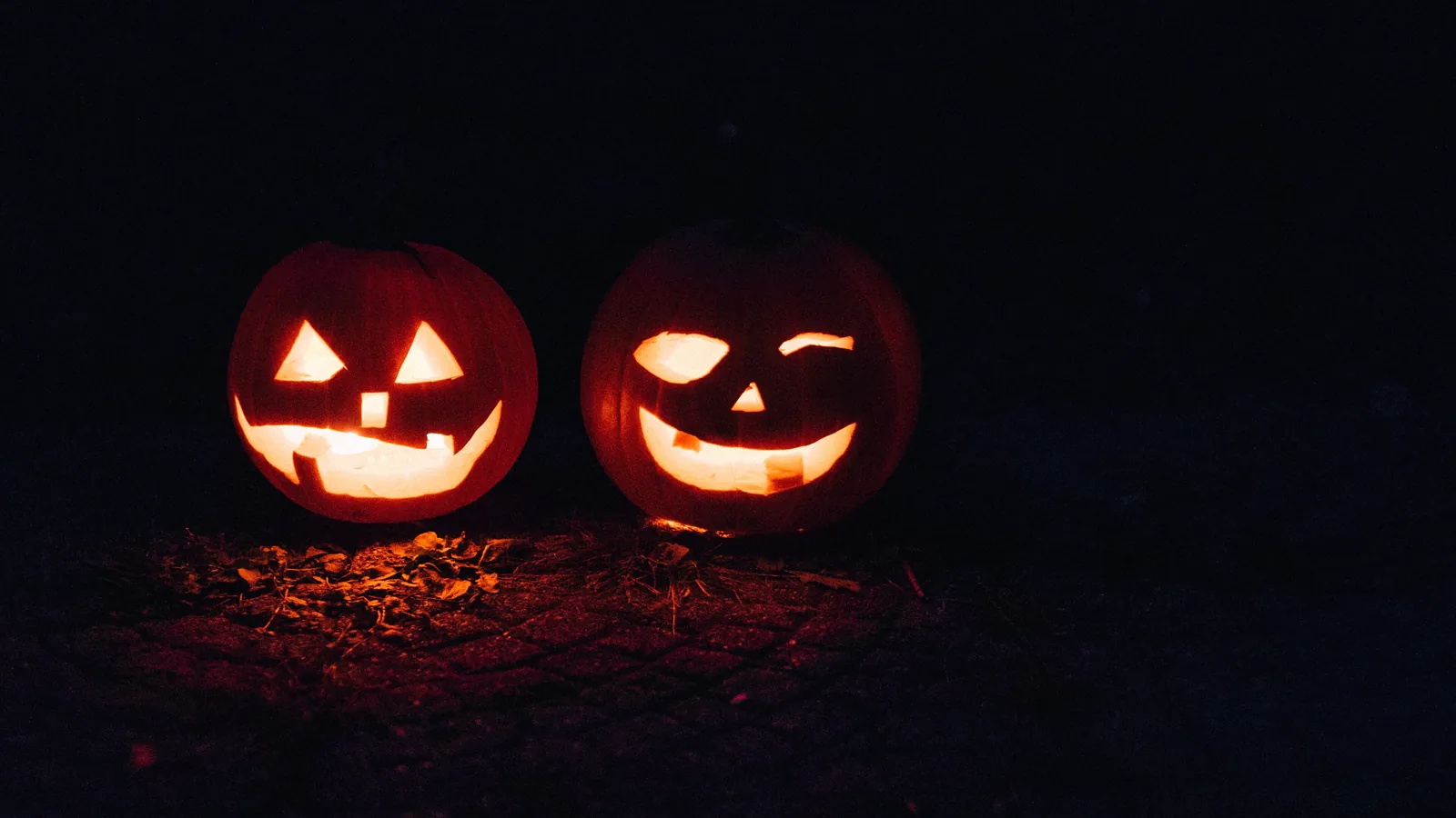 Two lit jack-o'-lanterns glowing in the dark