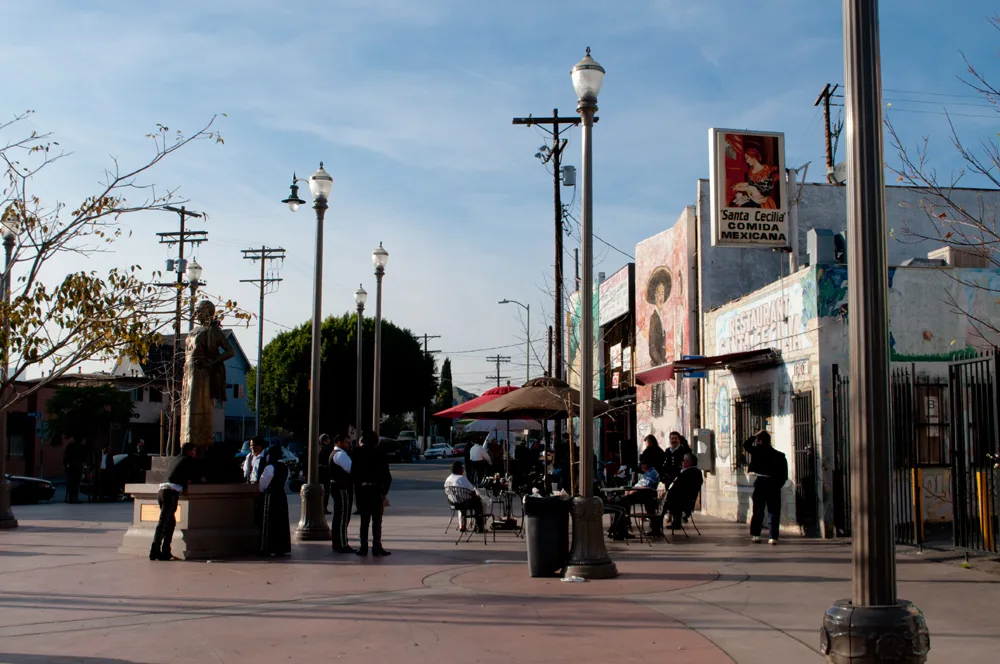 Mariachi Plaza in Boyle Heights with lampposts, a paved plaza and storefronts