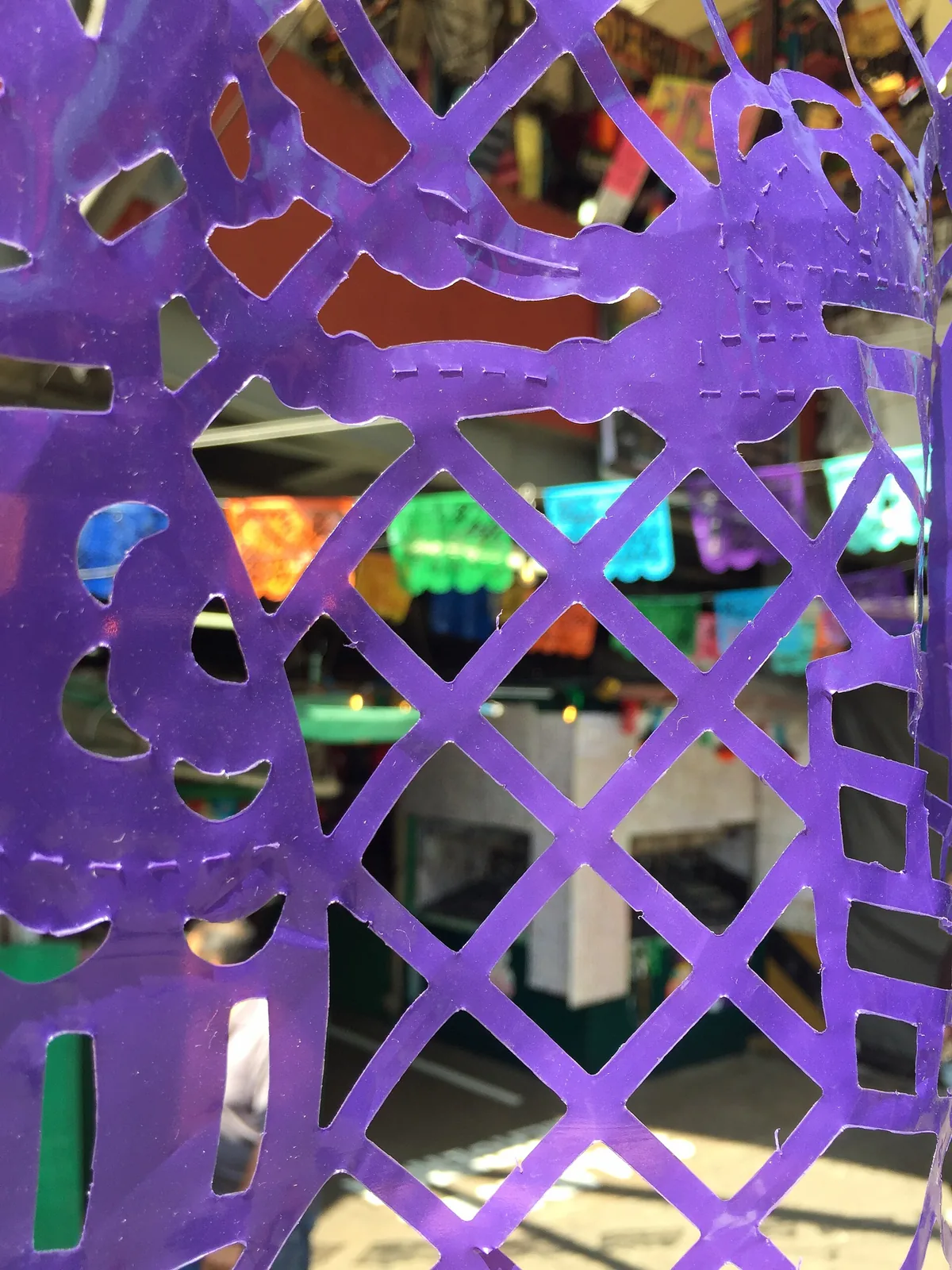 Purple papel picado with a cut lattice pattern hanging at a market